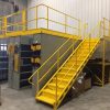 Yellow mezzanine staircase in a warehouse setting.